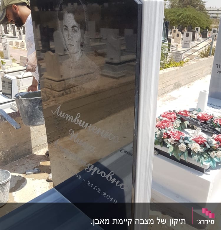 מצבה שחורה עם חריטה ותמונה בבית קברות